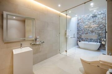 Modern bathroom with glass shower and stone accent wall