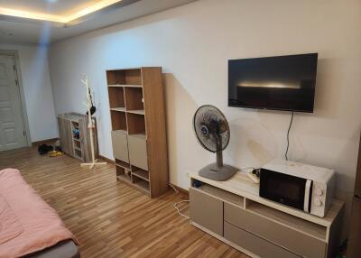 Bedroom with wooden flooring, modern shelving, wall-mounted TV, and small appliances.