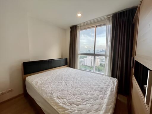 A bright bedroom with a large window and a double bed