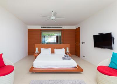 Modern bedroom with a bed, seating area, and wall-mounted TV