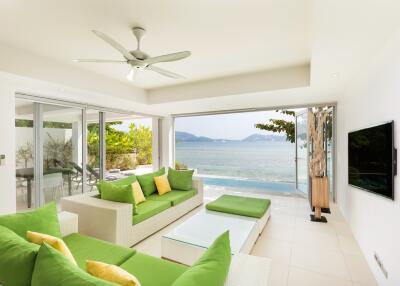 Bright living room with green sofas, glass coffee table, and ocean view