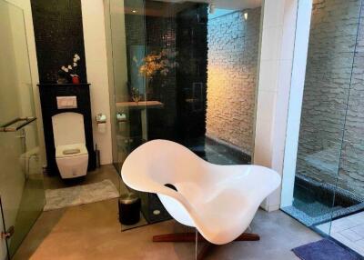 Modern bathroom with unique chair and glass-enclosed shower