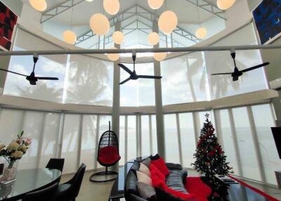 Modern living room with large windows, hanging lights, and ceiling fans