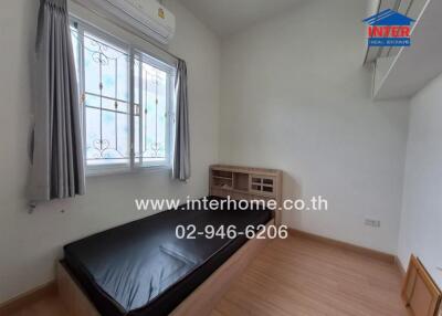 Simple bedroom with single bed, window with curtains, and air conditioning.