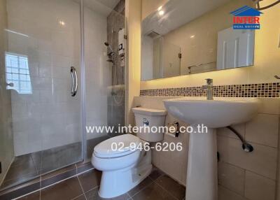 Modern bathroom with a glass shower enclosure, toilet, and sink.