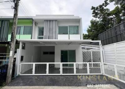 Front view of a modern two-story house with white exterior and gated driveway