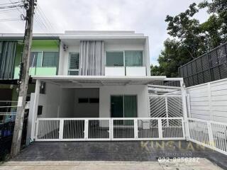 Front view of a modern two-story house with white exterior and gated driveway