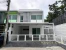 Front view of a modern two-story house with white exterior and gated driveway