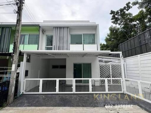 Front view of a modern two-story house with white exterior and gated driveway