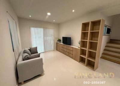 Modern living room with wooden flooring, TV unit, and ample lighting