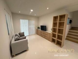 Modern living room with wooden flooring, TV unit, and ample lighting