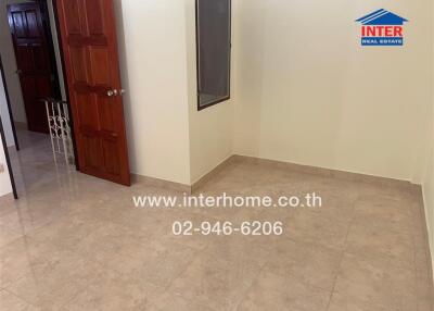 Interior view of an empty room with a wooden door and tiled floor