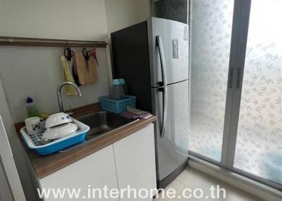 Compact kitchen with refrigerator, sink, and sliding glass door