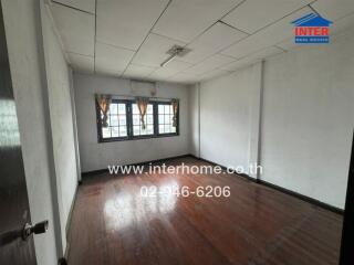 Bedroom with wooden flooring and curtains on windows