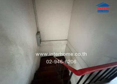 Narrow staircase with wooden stairs and a red handrail