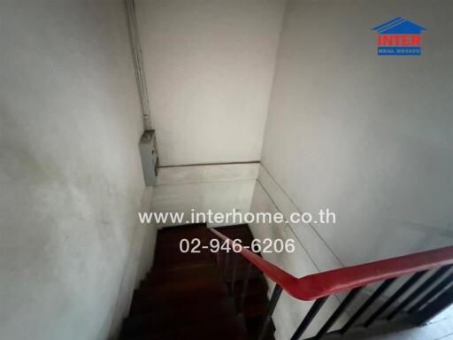 Narrow staircase with wooden stairs and a red handrail