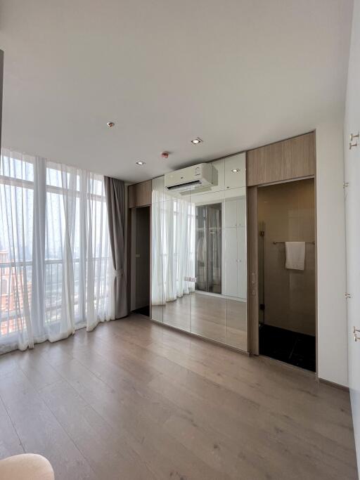 Modern bedroom with large windows, hardwood flooring, and a built-in wardrobe