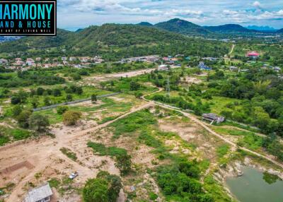 Aerial view of a vast area of land with surrounding greenery and distant mountains.