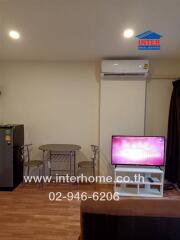 Living area with a table, chairs, refrigerator, air conditioner, and TV