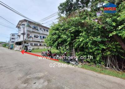 Street view of a residential area with a building in the background and trees on the side