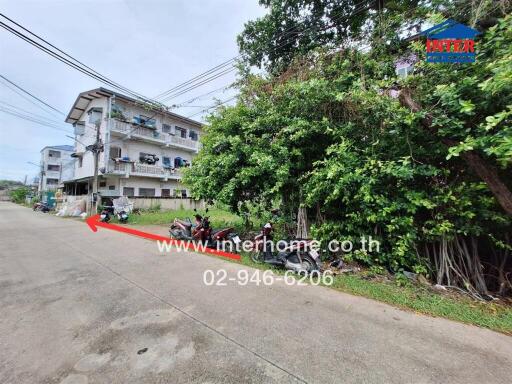 Street view of a residential area with a building in the background and trees on the side