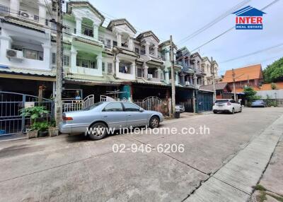 Street view of multi-story residential buildings with cars parked in front