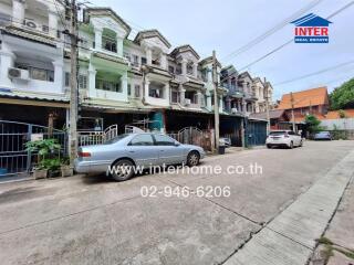 Street view of multi-story residential buildings with cars parked in front