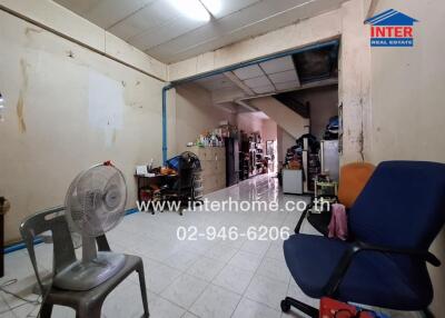 Interior of a sparsely furnished room with chairs, fan, and shelves