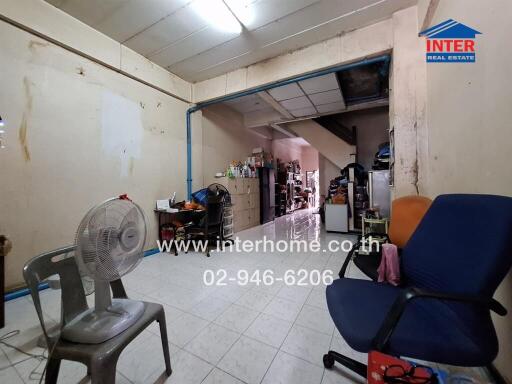 Interior of a sparsely furnished room with chairs, fan, and shelves