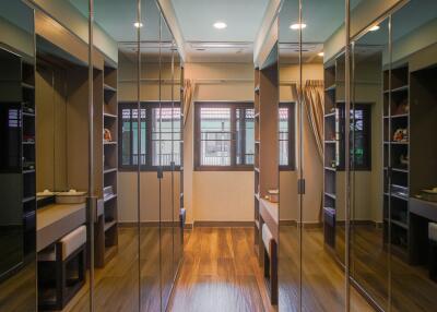 Spacious walk-in closet with mirrored doors and hardwood floors