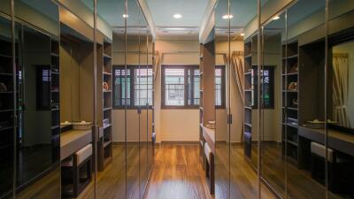 Spacious walk-in closet with mirrored doors and hardwood floors