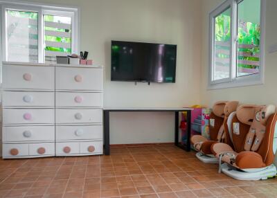 Bedroom with dresser, wall-mounted TV, and children