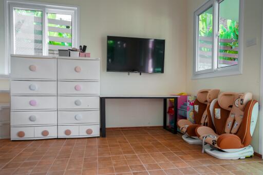 Bedroom with dresser, wall-mounted TV, and children