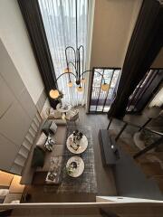 Aerial view of a modern living room with large windows, stylish furniture, and a chandelier