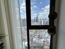 View from a window in a high-rise apartment overlooking a city skyline