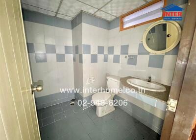 Bathroom with tiled walls and floor, toilet, and sink with mirror