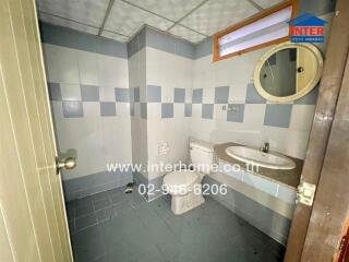 Bathroom with tiled walls and floor, toilet, and sink with mirror