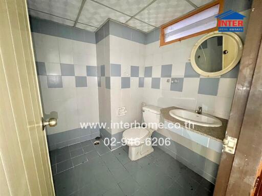 Bathroom with tiled walls and floor, toilet, and sink with mirror