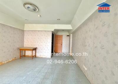 Unfurnished living room with tiled floor, wallpapered walls, and a wooden table