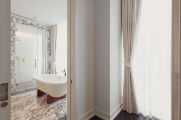 Bright marble bathroom with freestanding tub and large window