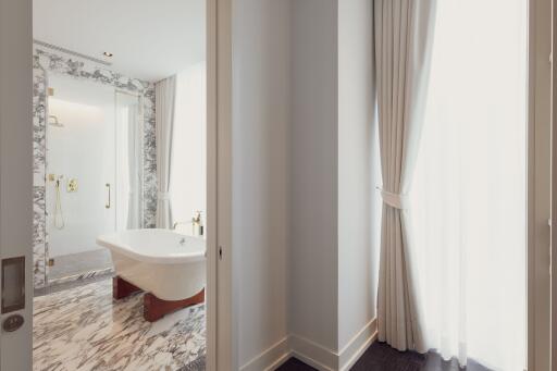 Bright marble bathroom with freestanding tub and large window