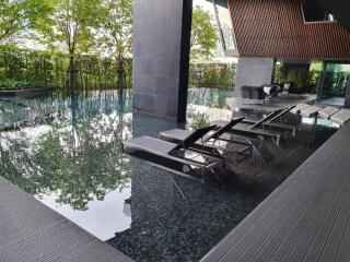 Luxury swimming pool area with lounge chairs and greenery