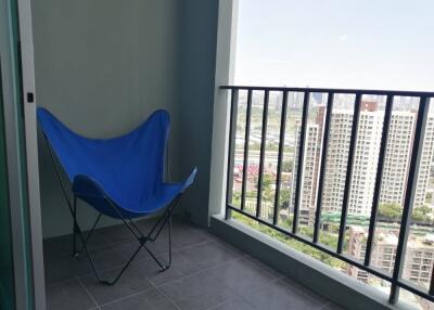 Balcony with a view of high-rise buildings and a blue folding chair