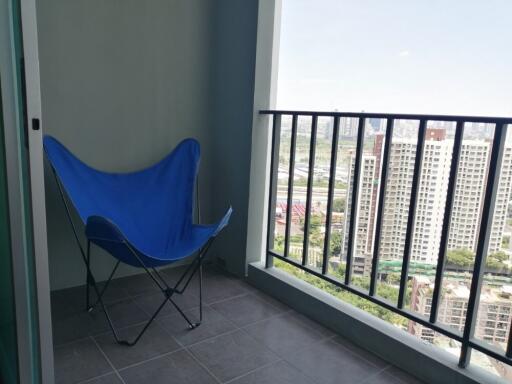 Balcony with a view of high-rise buildings and a blue folding chair