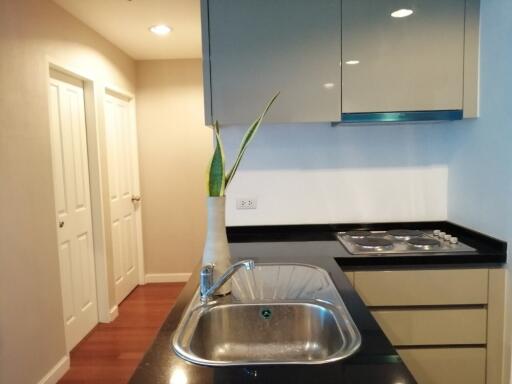 Modern kitchen with sink, countertop stove, and hallway view