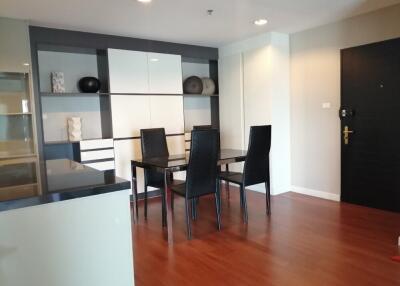 Modern dining room with black table and chairs, wooden floor, and built-in shelves