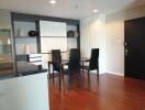 Modern dining room with black table and chairs, wooden floor, and built-in shelves