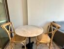 Small dining area with round marble table and wooden chairs