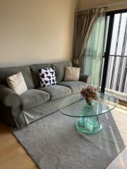 Living room with a sofa, glass coffee table, and balcony access