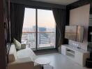 Living room with city view, balcony window, and a TV